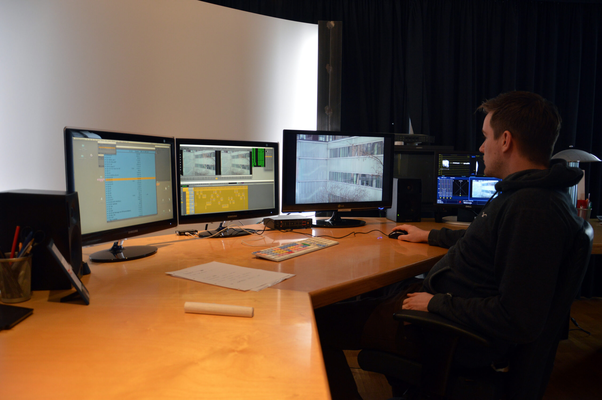 Editor trabajando frente a dos monitores en una sala de edición digital