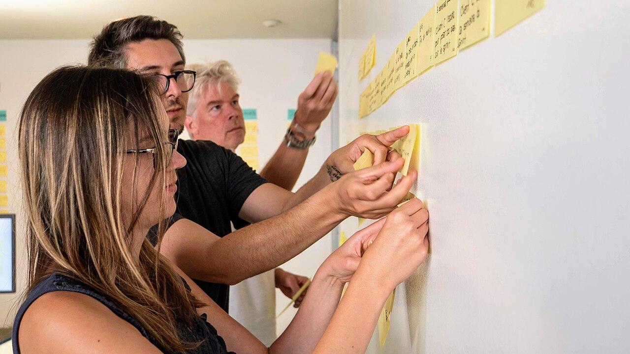 Equipo creativo organizando notas adhesivas durante un taller de diseño