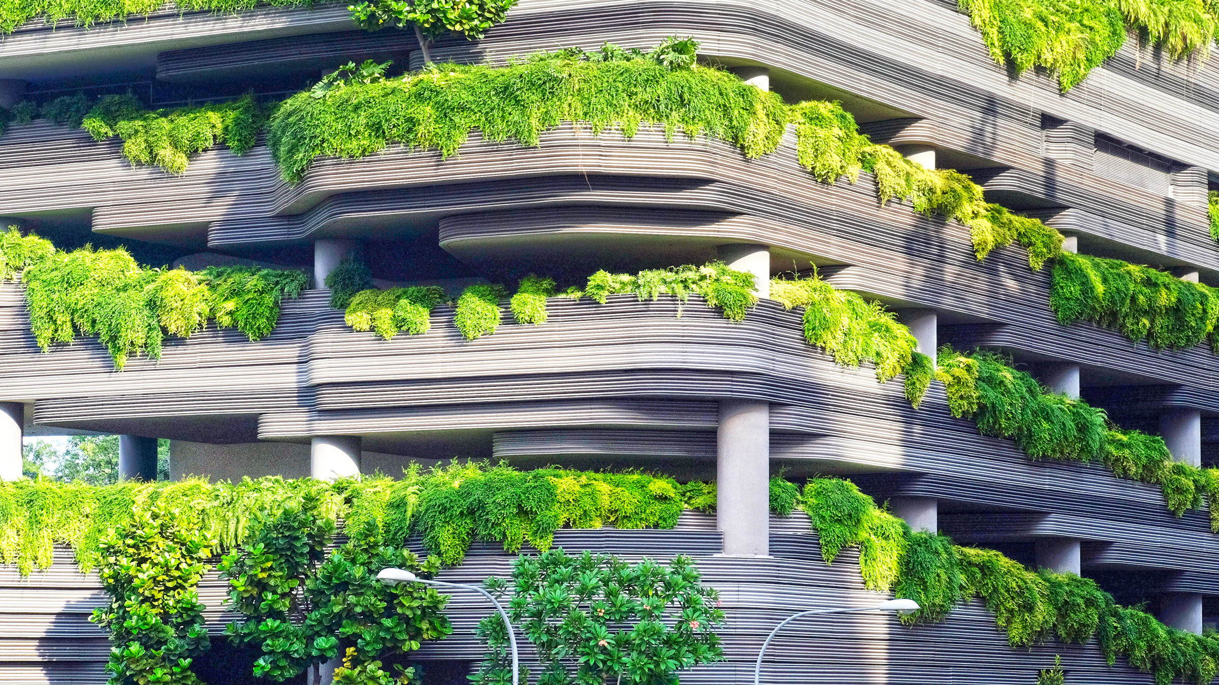 Fachada contemporánea con terrazas cubiertas por vegetación