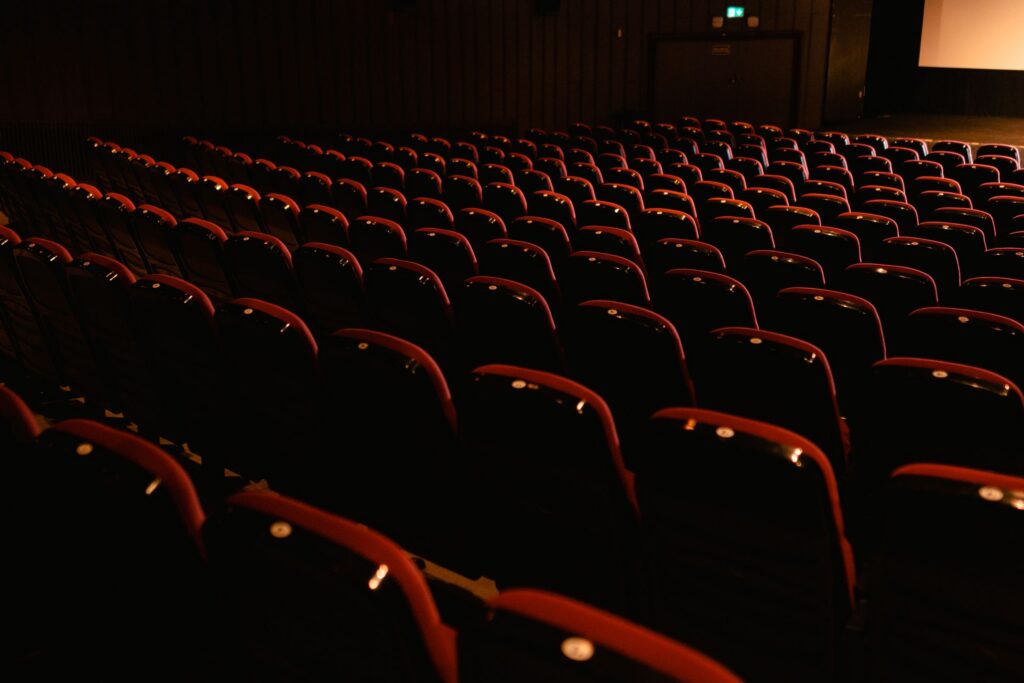 Filas de butacas rojas frente a la pantalla de una sala cinematográfica