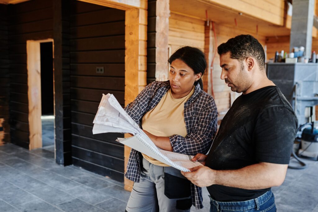 Dos profesionales revisan planos dentro de una construcción