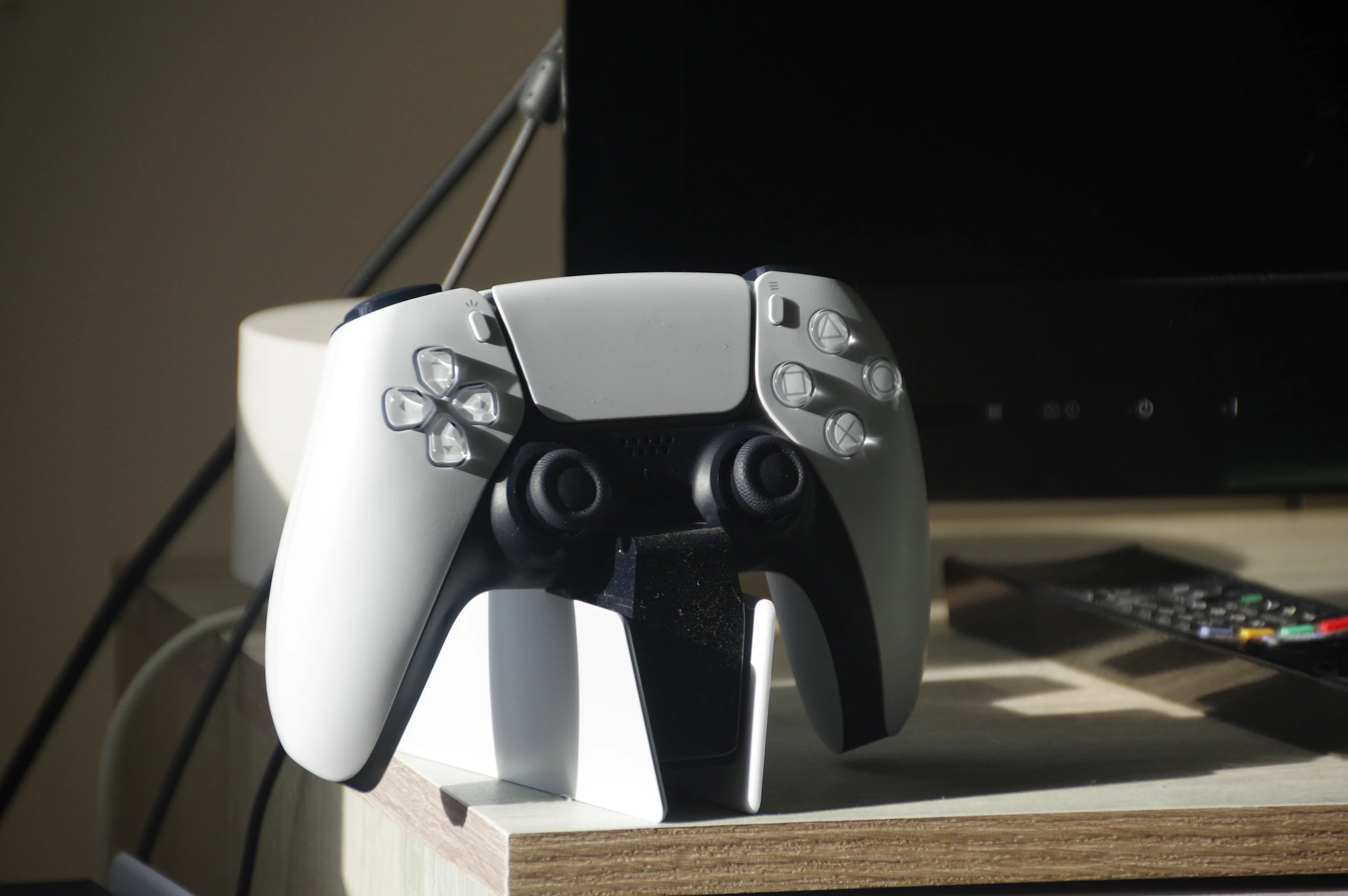 Control de videojuegos blanco sobre una base en un escritorio de madera