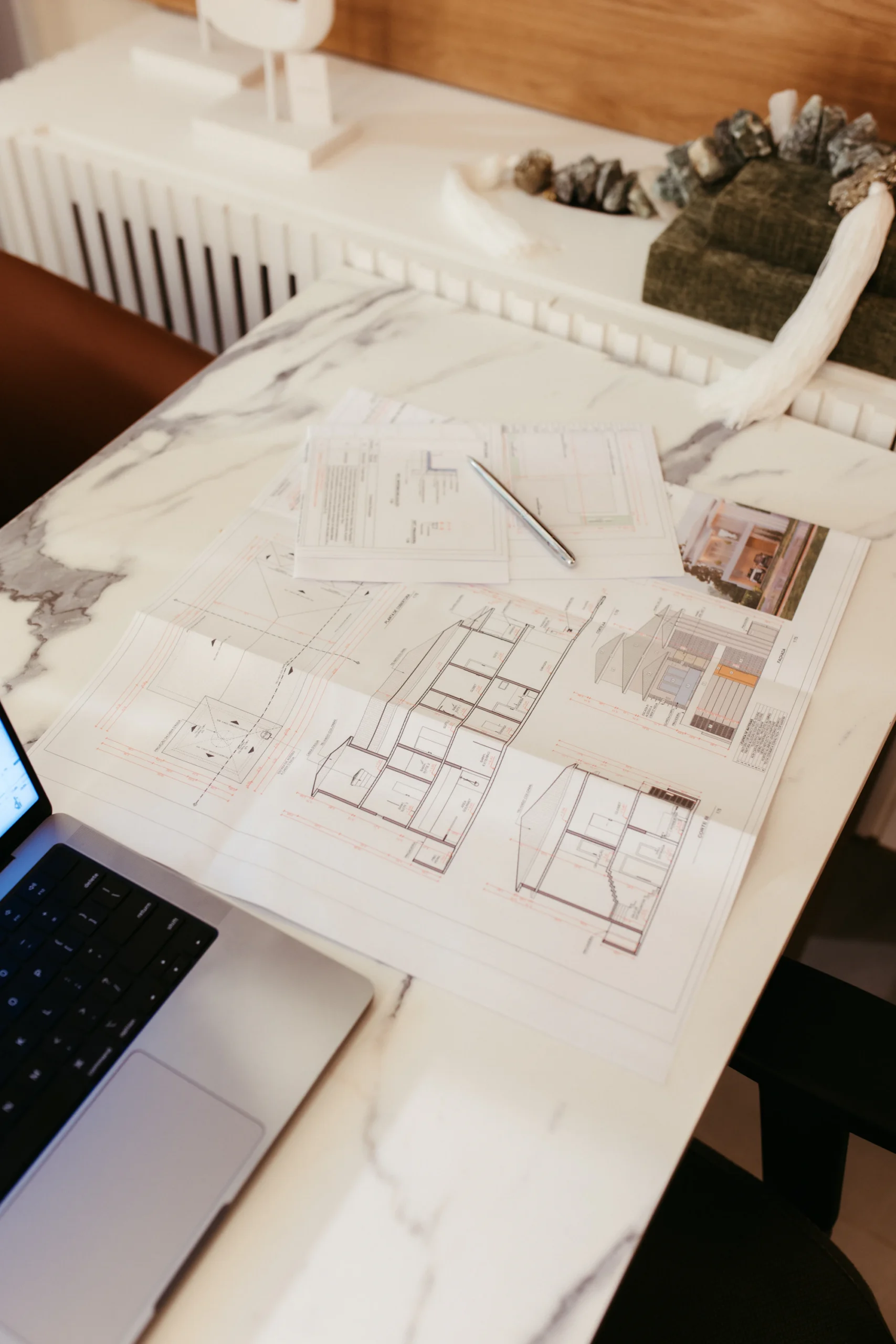 Planos arquitectónicos y computadora portátil sobre una mesa de trabajo