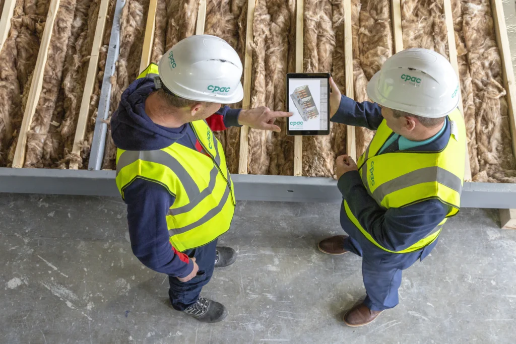Dos profesionales de construcción revisan planos en una tableta dentro de una obra