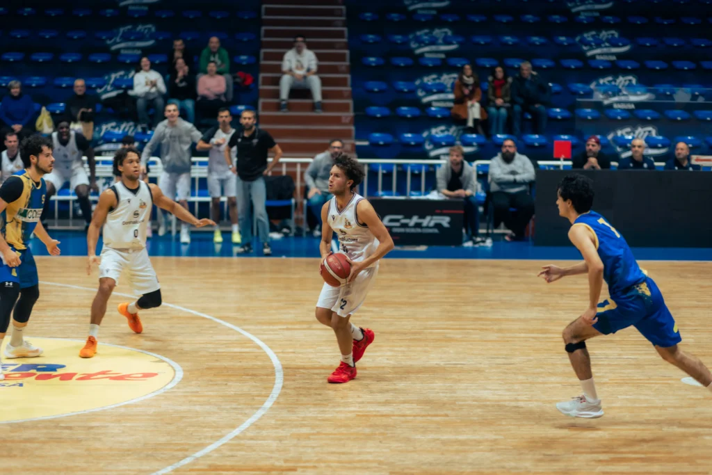 Jugadores de basquetbol en movimiento sobre una cancha de madera