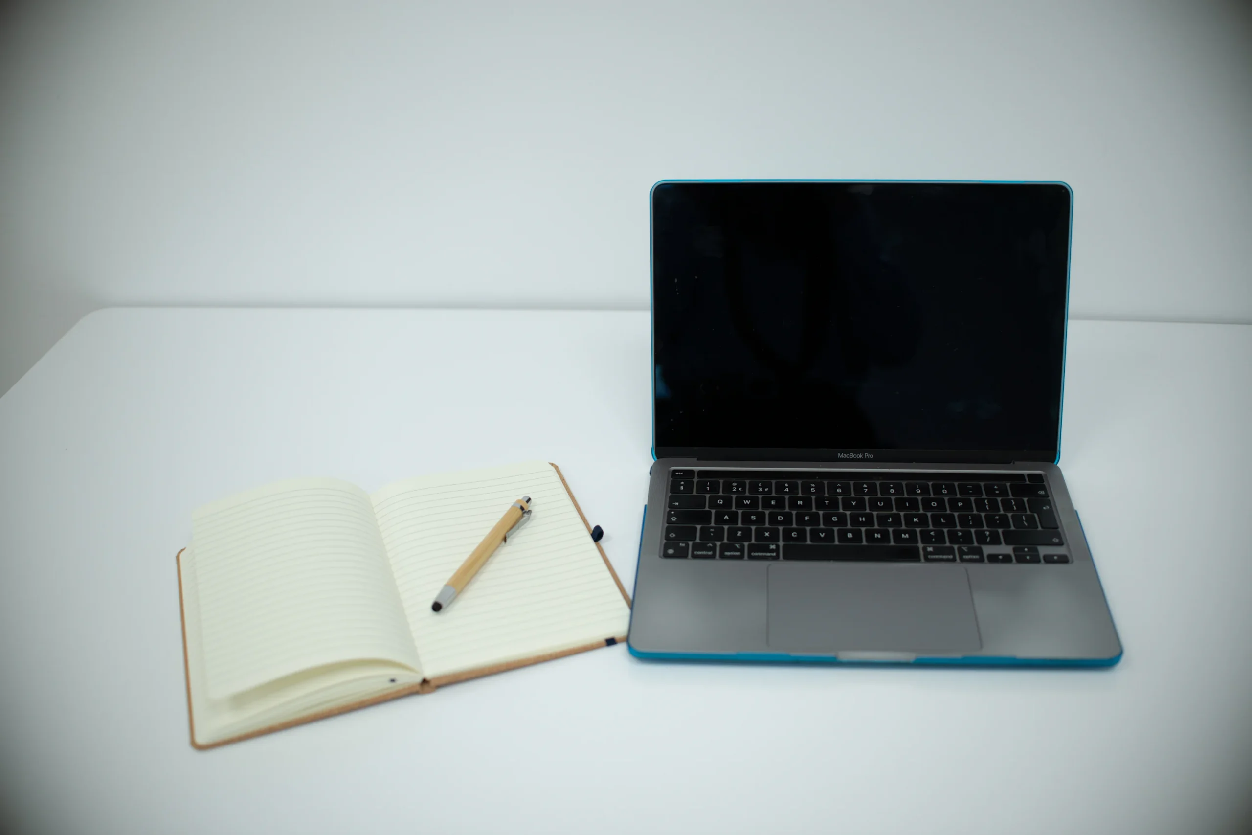 Computadora portátil y libreta abierta sobre un escritorio de trabajo