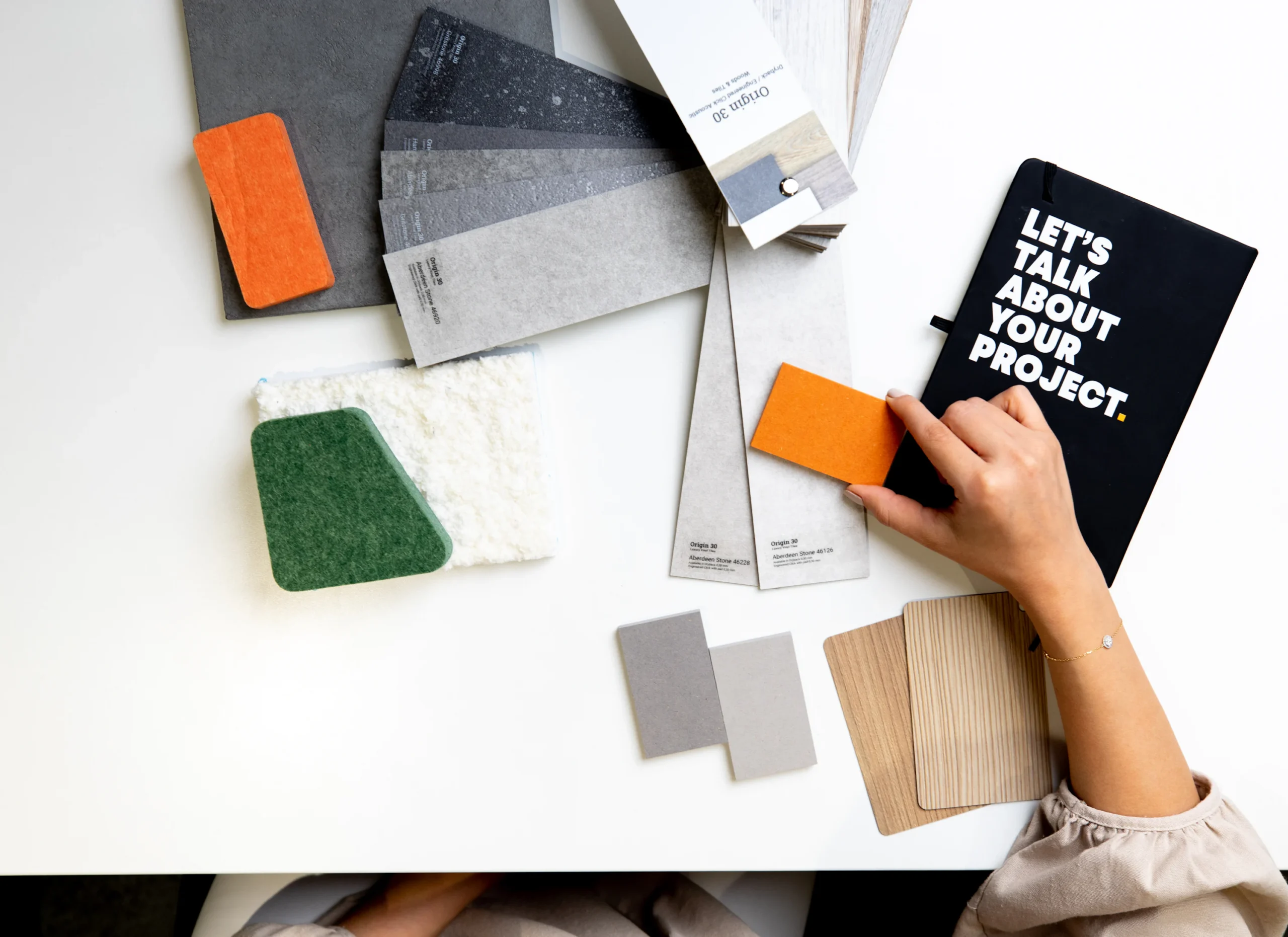 Persona comparando una muestra naranja con materiales sobre una mesa de diseño