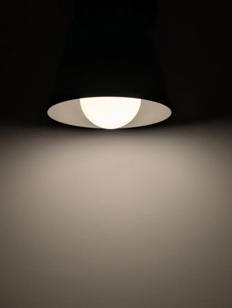 Lámpara colgante proyectando luz cálida sobre un muro interior